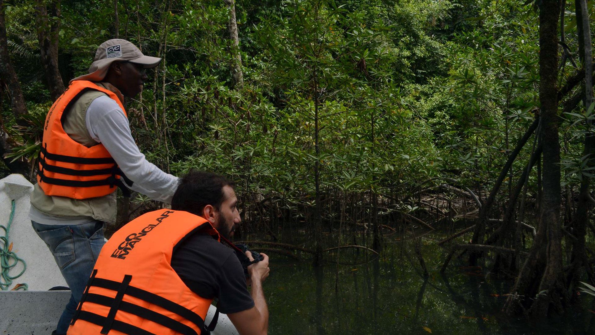 Fotografía de un guía y un turista con cámara fotográfica recorrido por los manglares en lancha